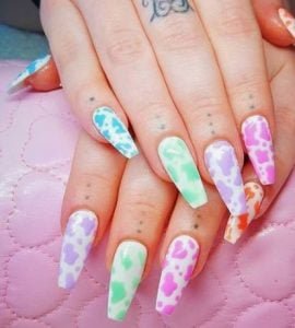 unhas multicoloridas com design de vaca