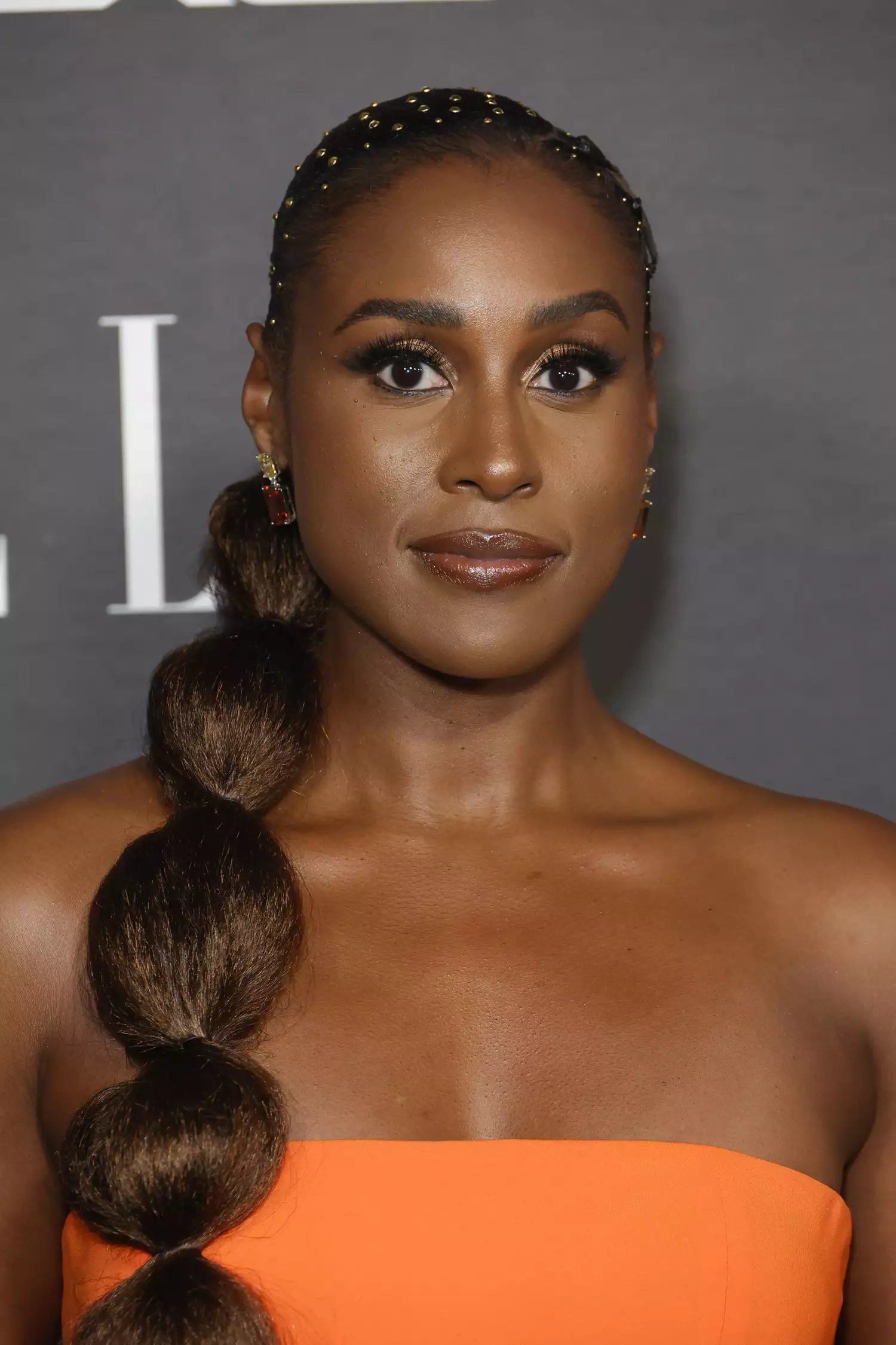 Issa Rae com rabo de cavalo longo e joias no cabelo